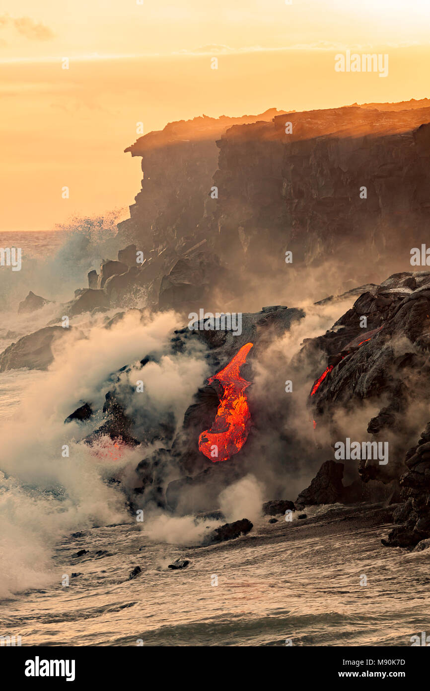 Acqua di mare e roccia fusa splatter insieme come un'onda si blocca sulla lava pahoehoe che fluisce dal Kilauea nell'Oceano Pacifico vicino Kalapana, è grande Foto Stock