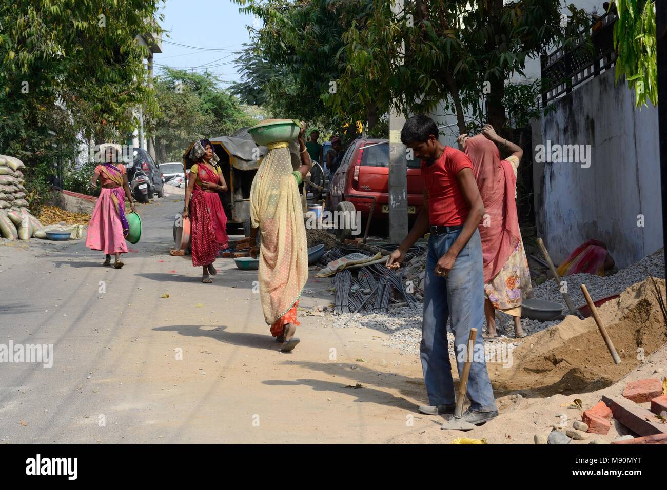 Le donne indiane che indossa sari lavorando in costruzione portante bocce di sabbia e pietre sulle loro teste per fare cemento per la costruzione di Udaipur Rajashan India Foto Stock