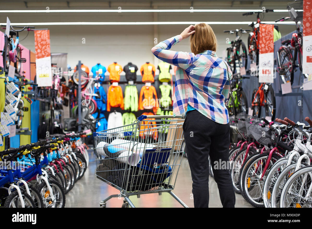 Donna con un carrello della spesa sceglie le merci in un negozio di sport Foto Stock