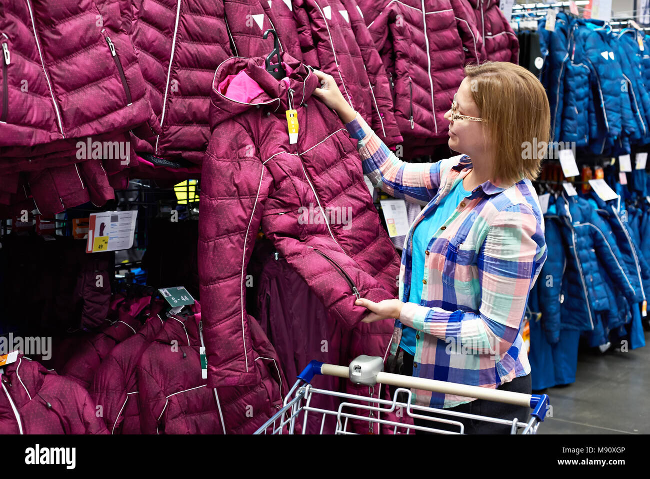La donna sceglie una giacca invernale in negozio Foto Stock