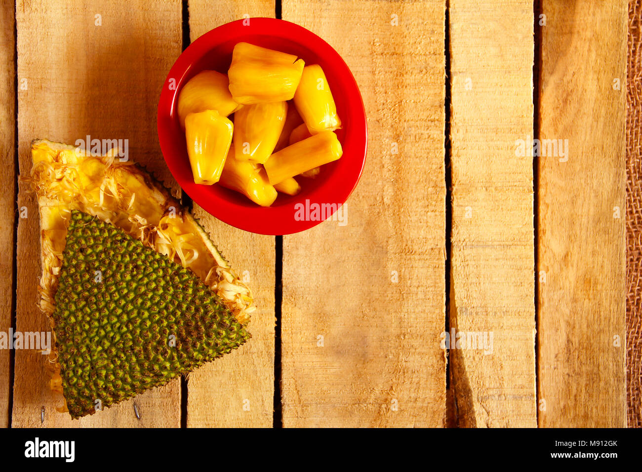 Vista superiore del recipiente rosso con cialde jackfruit jackfruit e pelle isolato su sfondo di legno Foto Stock