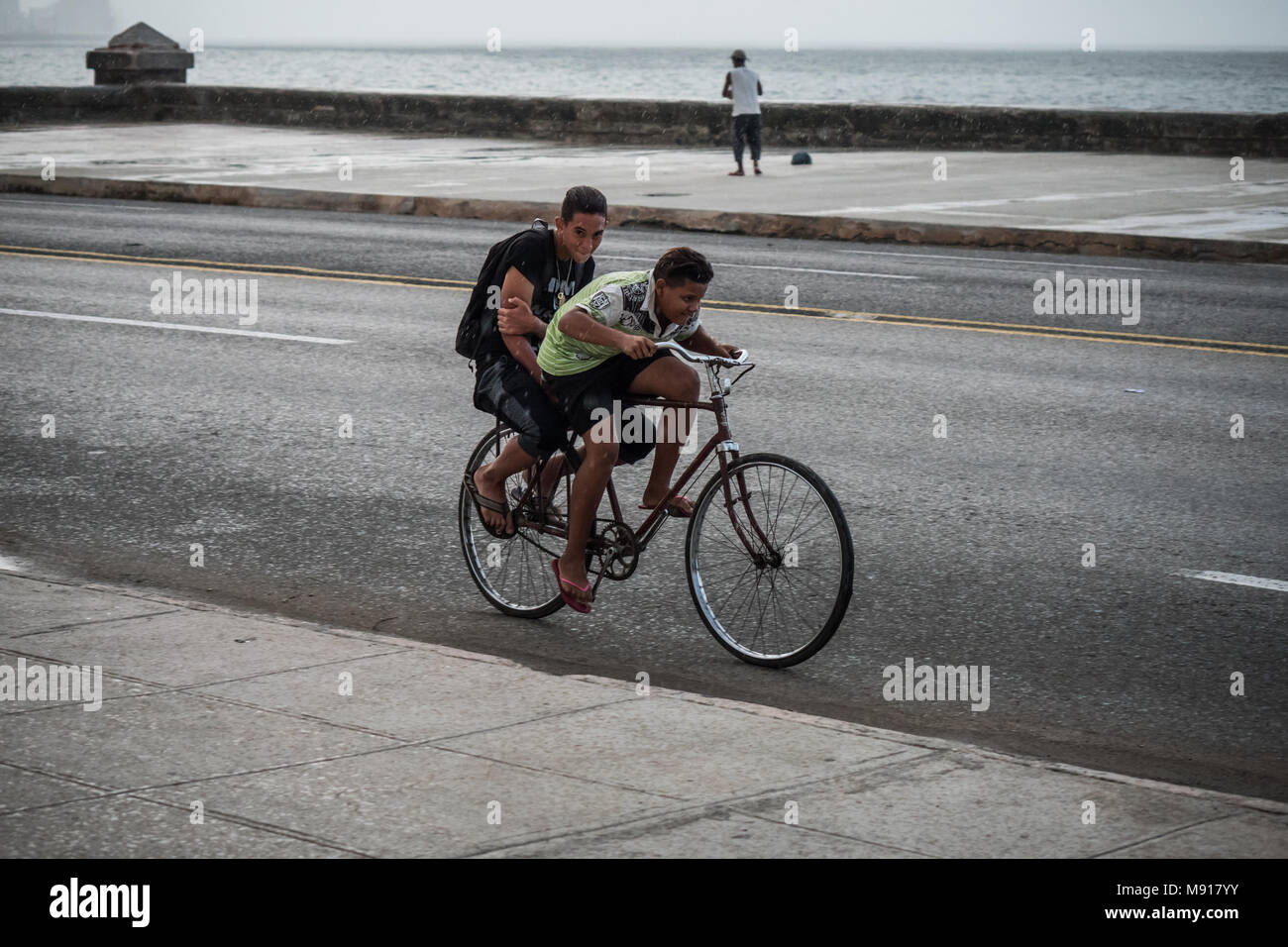 Due ragazzi su una bicicletta in heavy rain per Il Malecon, Havana, Cuba  Foto stock - Alamy