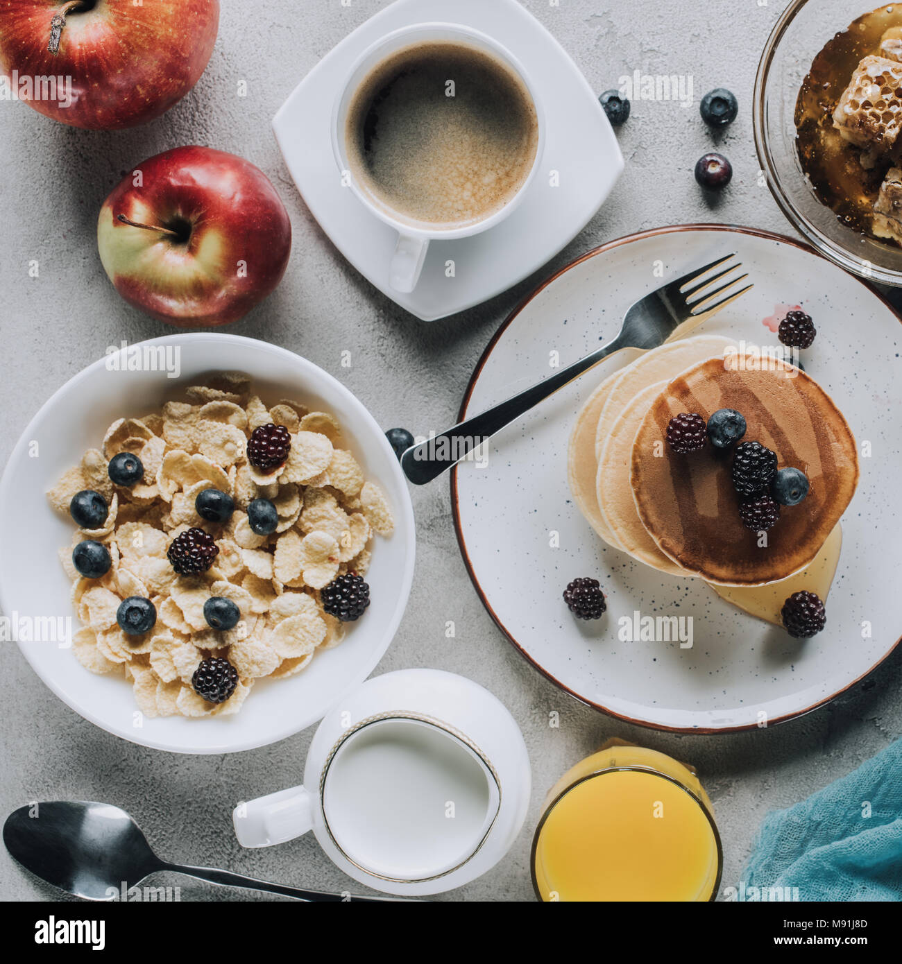Vista dall'alto di una gustosa colazione sana con pancake, frutta e muesli su grigio Foto Stock