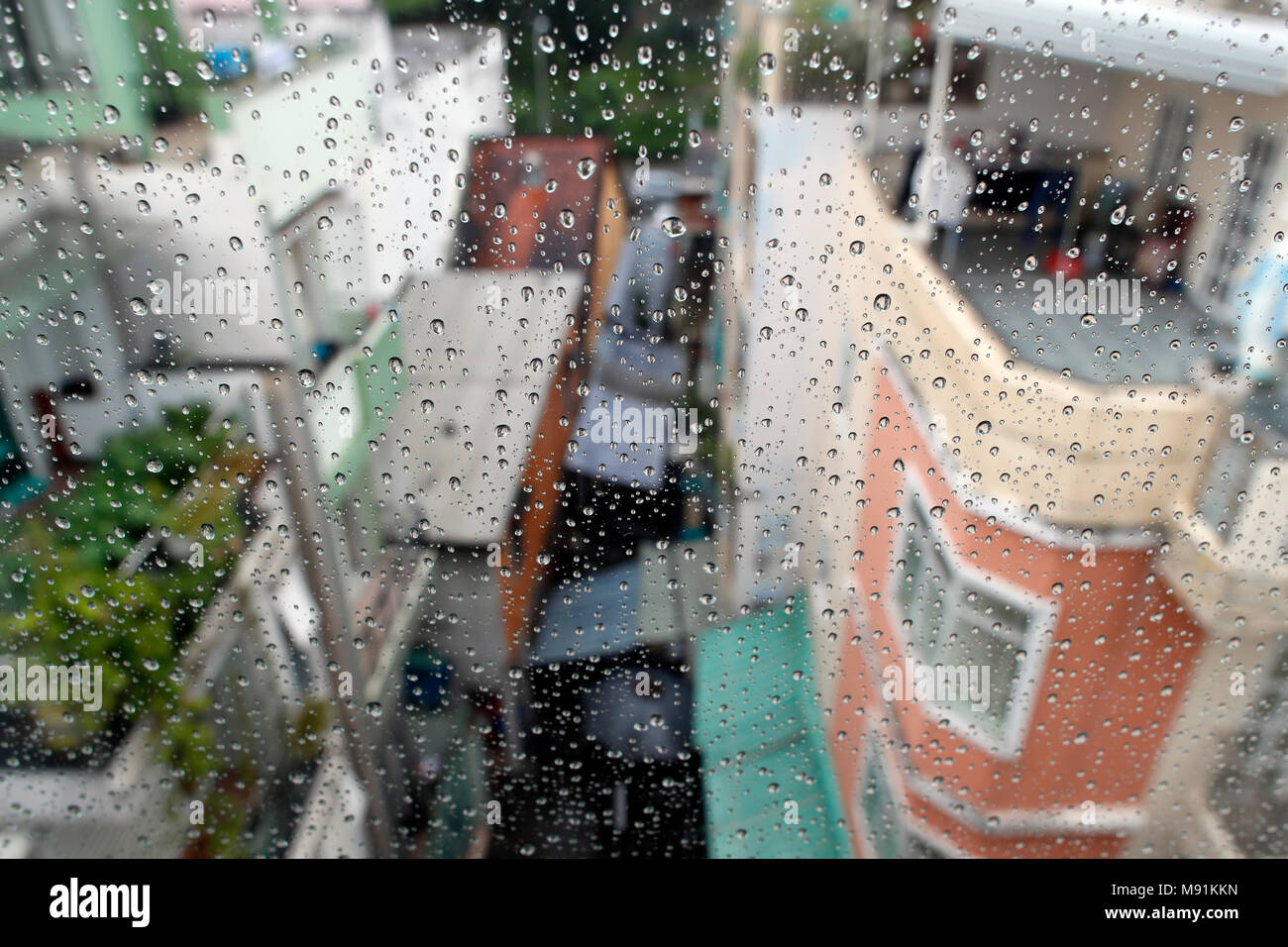 Stagione dei monsoni. close-up di gocce di pioggia sul vetro della finestra. Gocce di acqua di pioggia sulla finestra, scene di strada in background. Ho Chi Minh City. Il Vietnam. Foto Stock