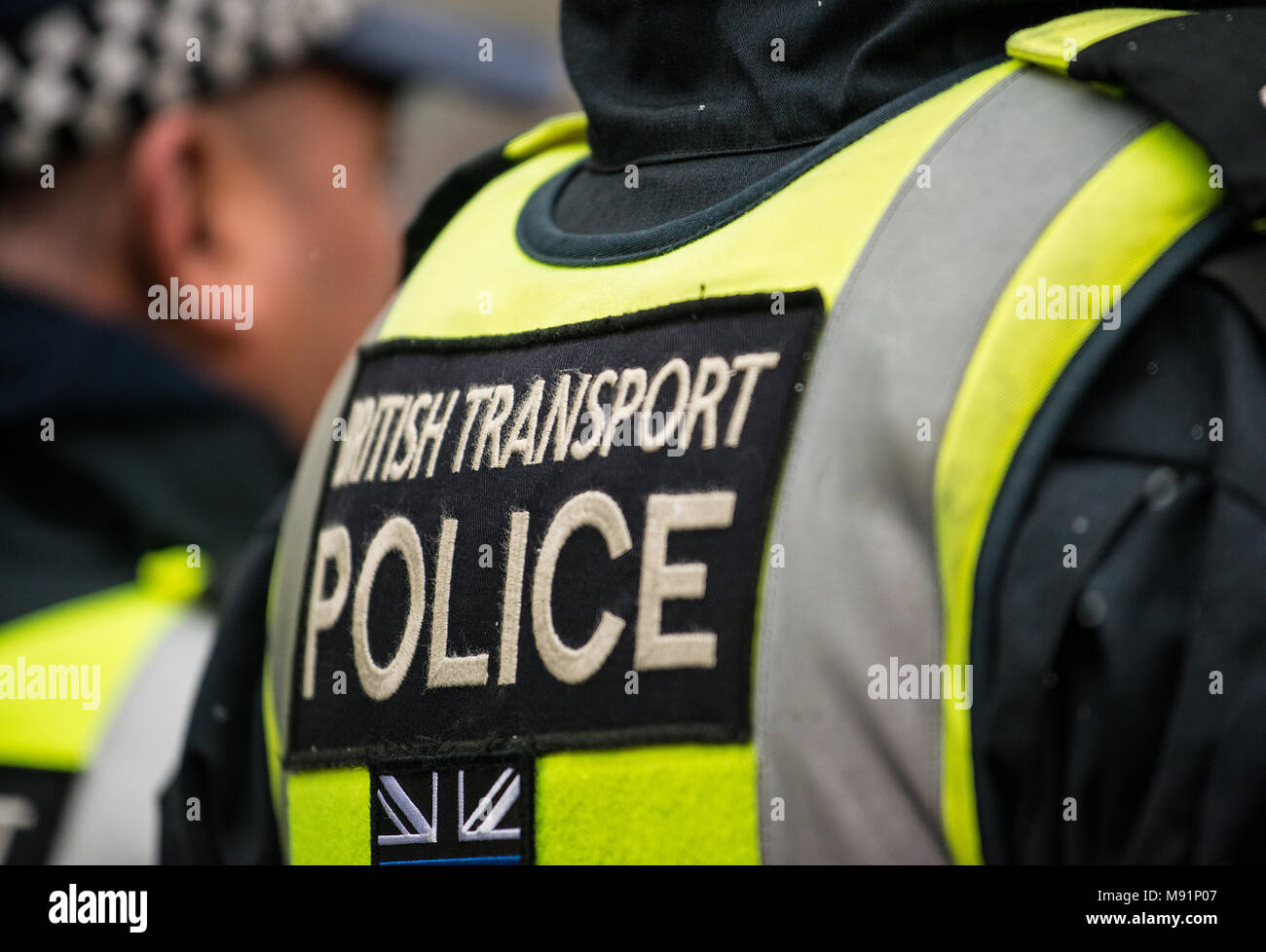 Funzionario di polizia con il suo ritorno alla telecamera con British Transport Police segno sul suo giubbotto stab. Foto Stock