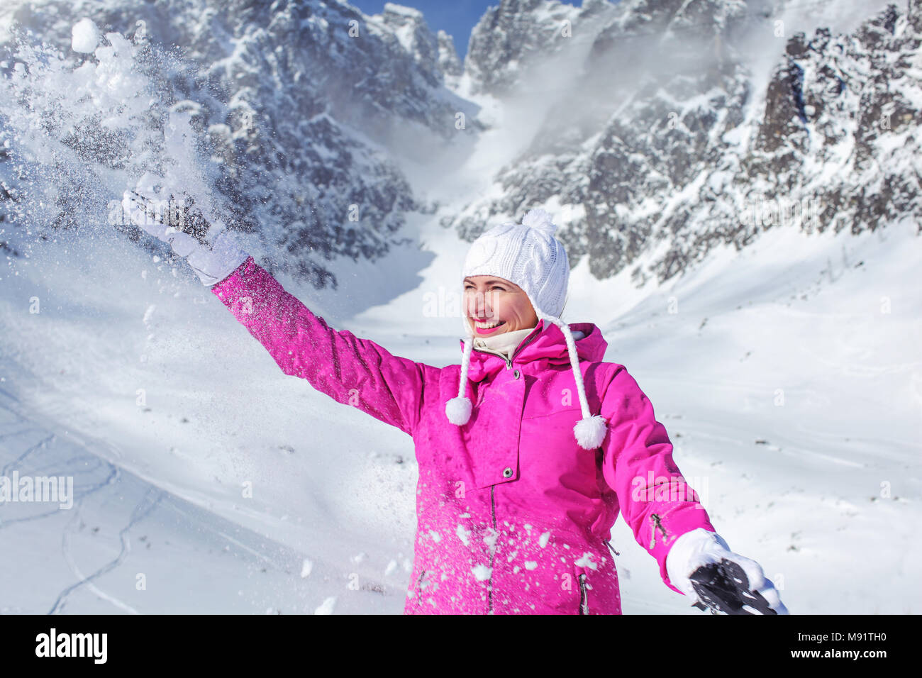 Giovane donna in rosa giacca da sci e guanti bianchi sorridente e gettando  la neve in aria di montagna in background. Skalnate pleso ski resort, Slova  Foto stock - Alamy