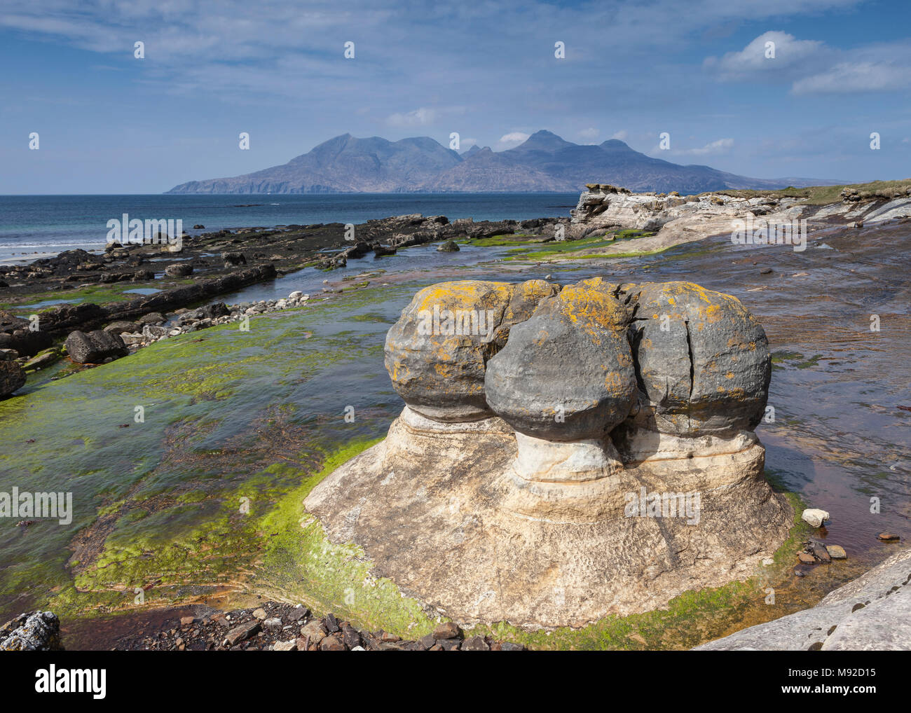 Concrezioni di arenaria presso la baia di Laig sull'Isola di Eigg, Ebridi Interne, Scozia. Le montagne in distanza sono sull'Isola di rum. Foto Stock