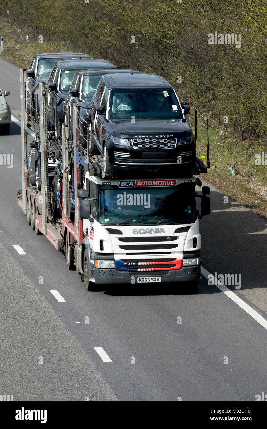 Un Scania BCA Automotive transporter portando nuovo Land Rover Automobili sulla autostrada M40, Warwickshire, Regno Unito Foto Stock