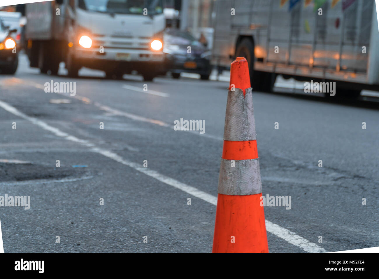 Cono stradale sul lato della strada trafficata al driver di attenzione intorno a condizioni pericolose Foto Stock