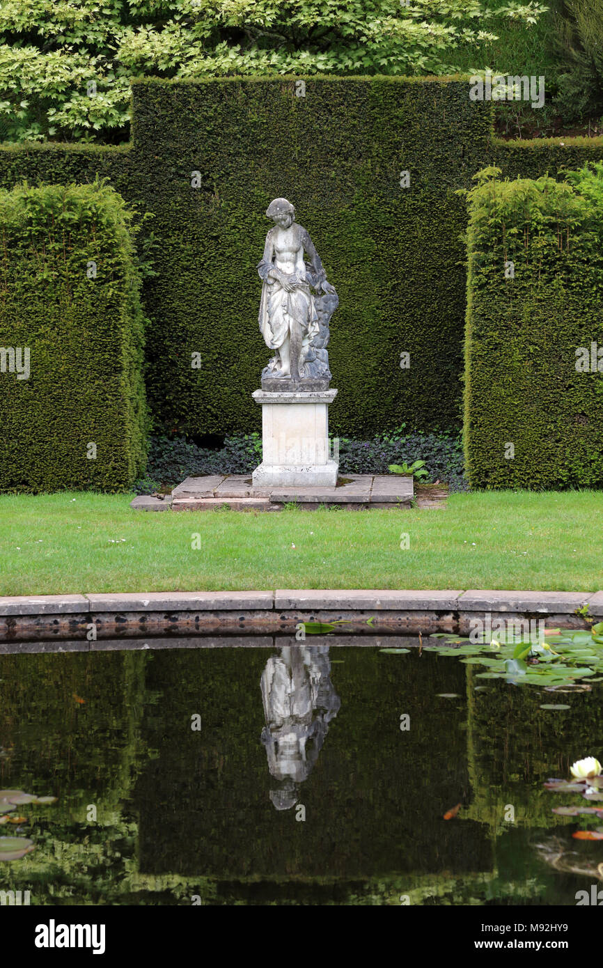 Una statua nel giardino con piscina a Knightshayes Court, Tiverton Devon, Regno Unito. Il palazzo e i giardini circostanti sono di proprietà del National Trust. Foto Stock