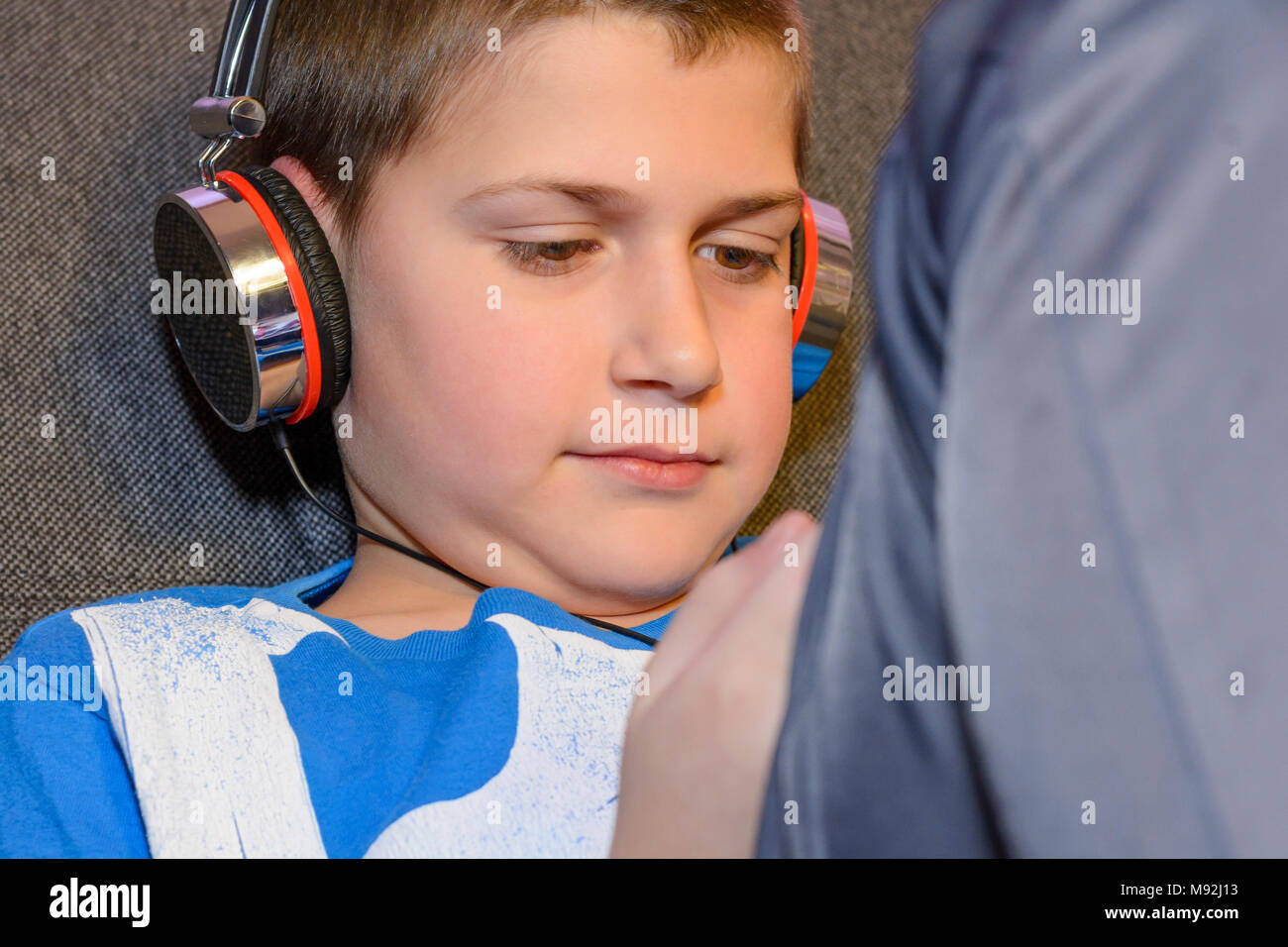 Ragazzo con le cuffie e il telefono cellulare in mano. Un ragazzo ascoltare musica dalle cuffie. Dipendenza da telefono cellulare nei bambini. Foto Stock