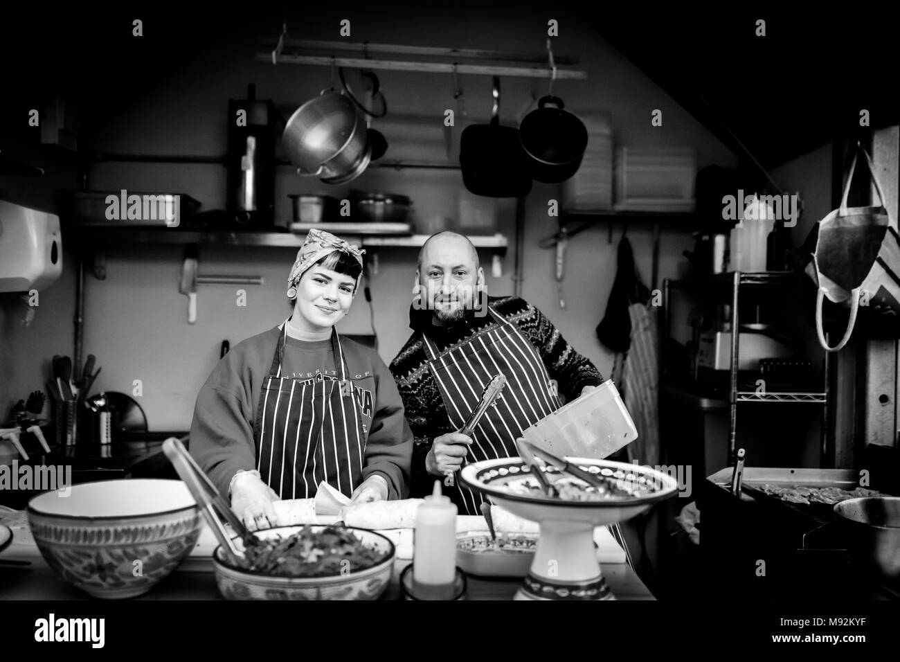 Il Caos, York il 16 febbraio 2018. La donna in una testa sciarpa e maschile chef in un grembiule su un cibo caldo stand, in stallo o in cucina in posa per la fotocamera Foto Stock