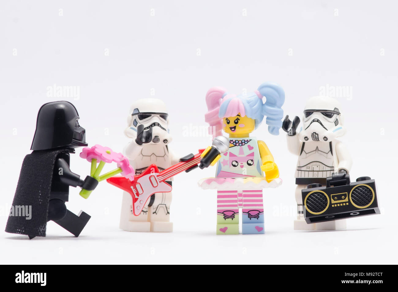 Lego Darth Vader dando fiore a n-pop ragazza con storm troopers, isolato su sfondo bianco. Foto Stock
