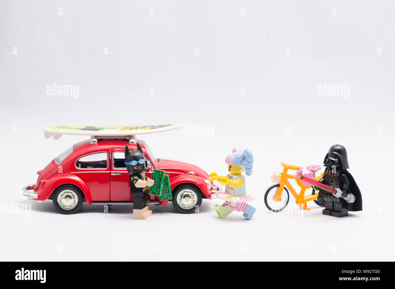 Lego Batman con auto e denaro essendo a caccia di n-pop girl, con Darth Vader guardando e tenendo un fiore. Foto Stock