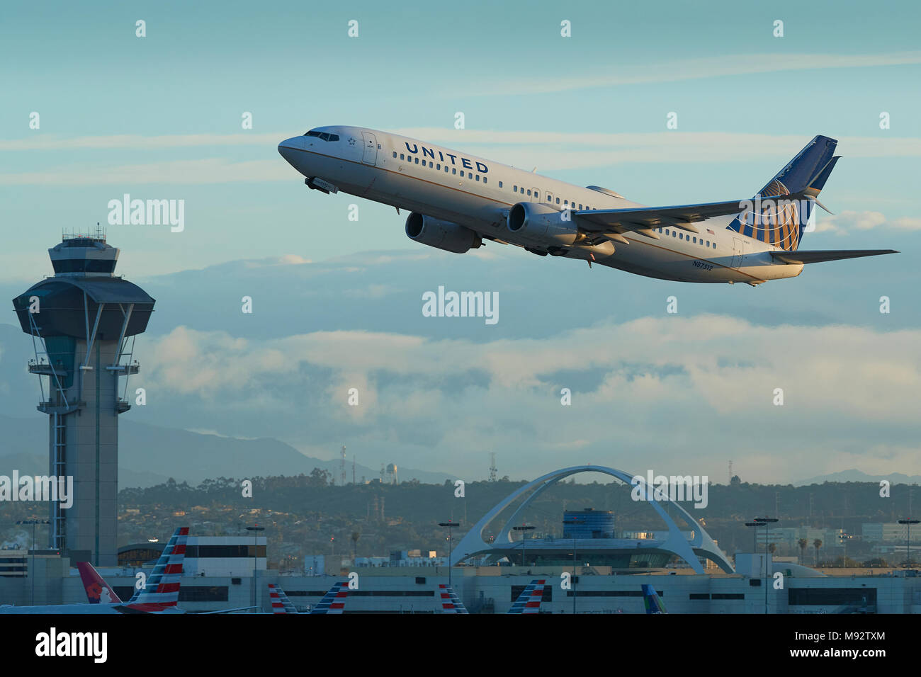 United Airlines Boeing 737-900 aereo Jet decollo dall'Aeroporto Internazionale di Los Angeles LAX. Il tema Building e la torre di controllo dietro. Foto Stock