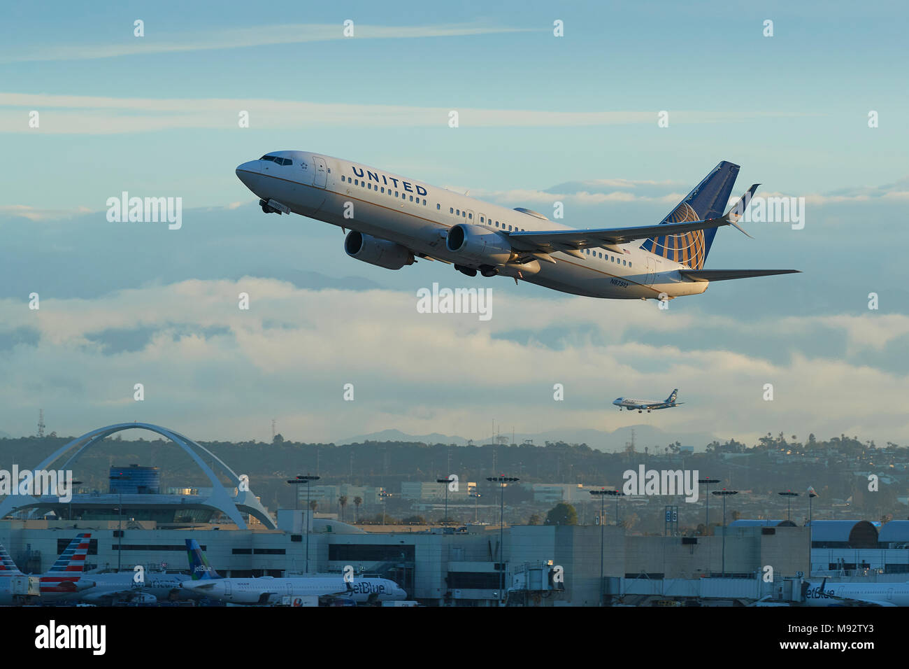 United Airlines Boeing 737-900 aereo Jet decollo dall'Aeroporto Internazionale di Los Angeles LAX. Il tema e la costruzione di un piano di sbarco dietro. Foto Stock