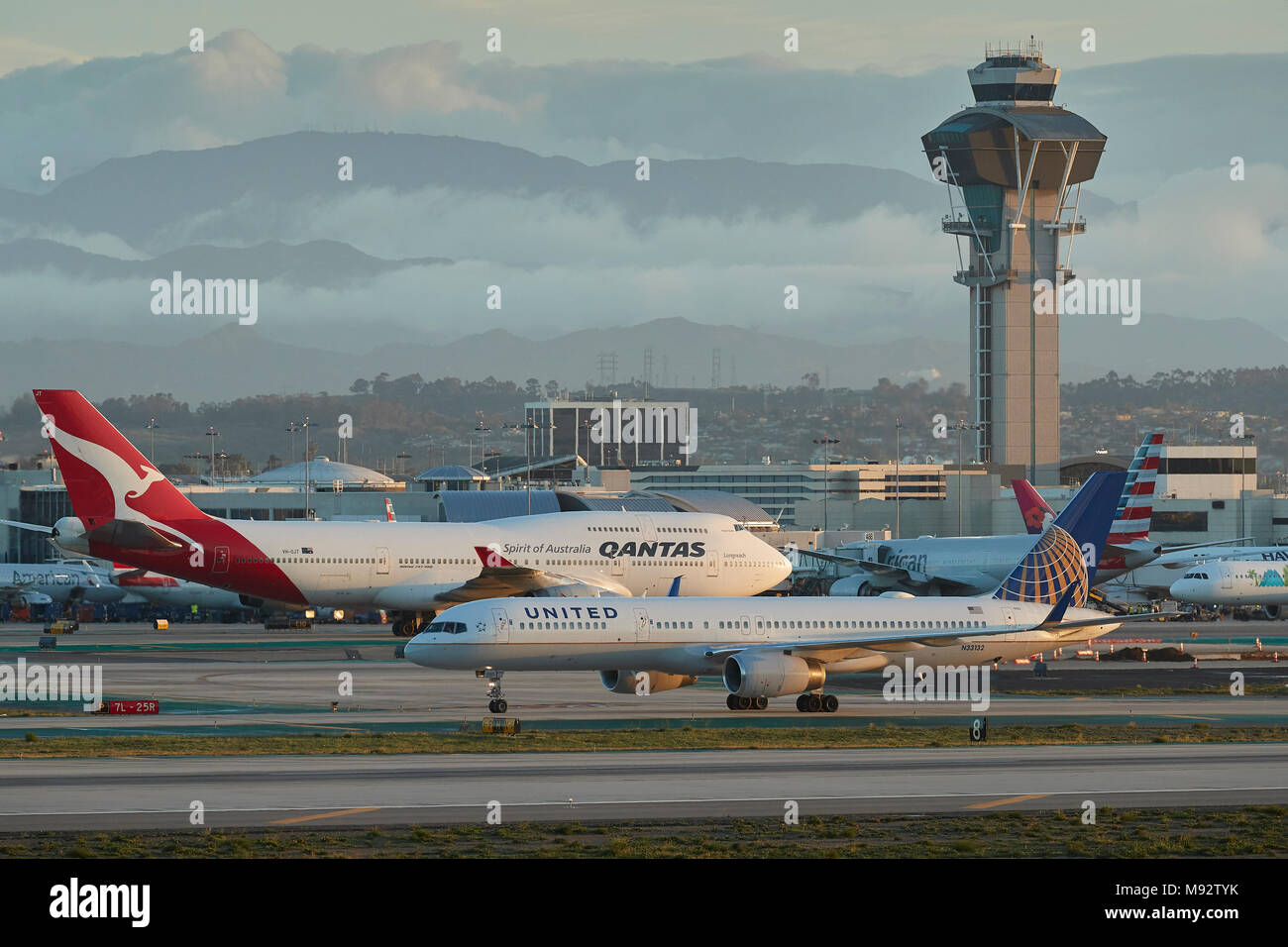 La mattina presto presso l'Aeroporto Internazionale di Los Angeles LAX della United Airlines Boeing 757 e Qantas Boeing 747-400, con la torre di controllo dietro. Foto Stock