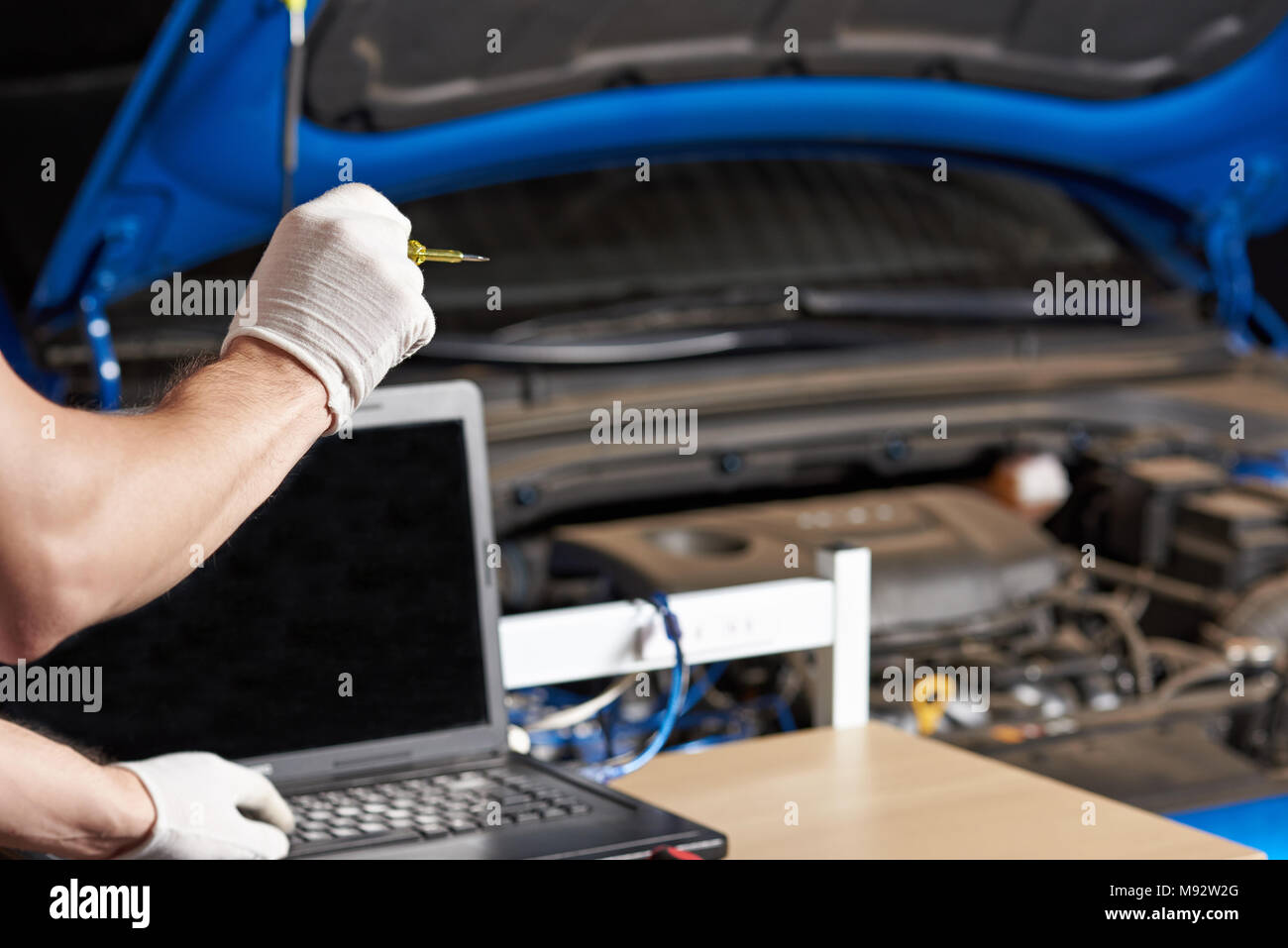 Mechanic uomo che fa del computer di auto diagnostica closeup. Mani di elettricista e facendo la manutenzione dell'automobile Foto Stock