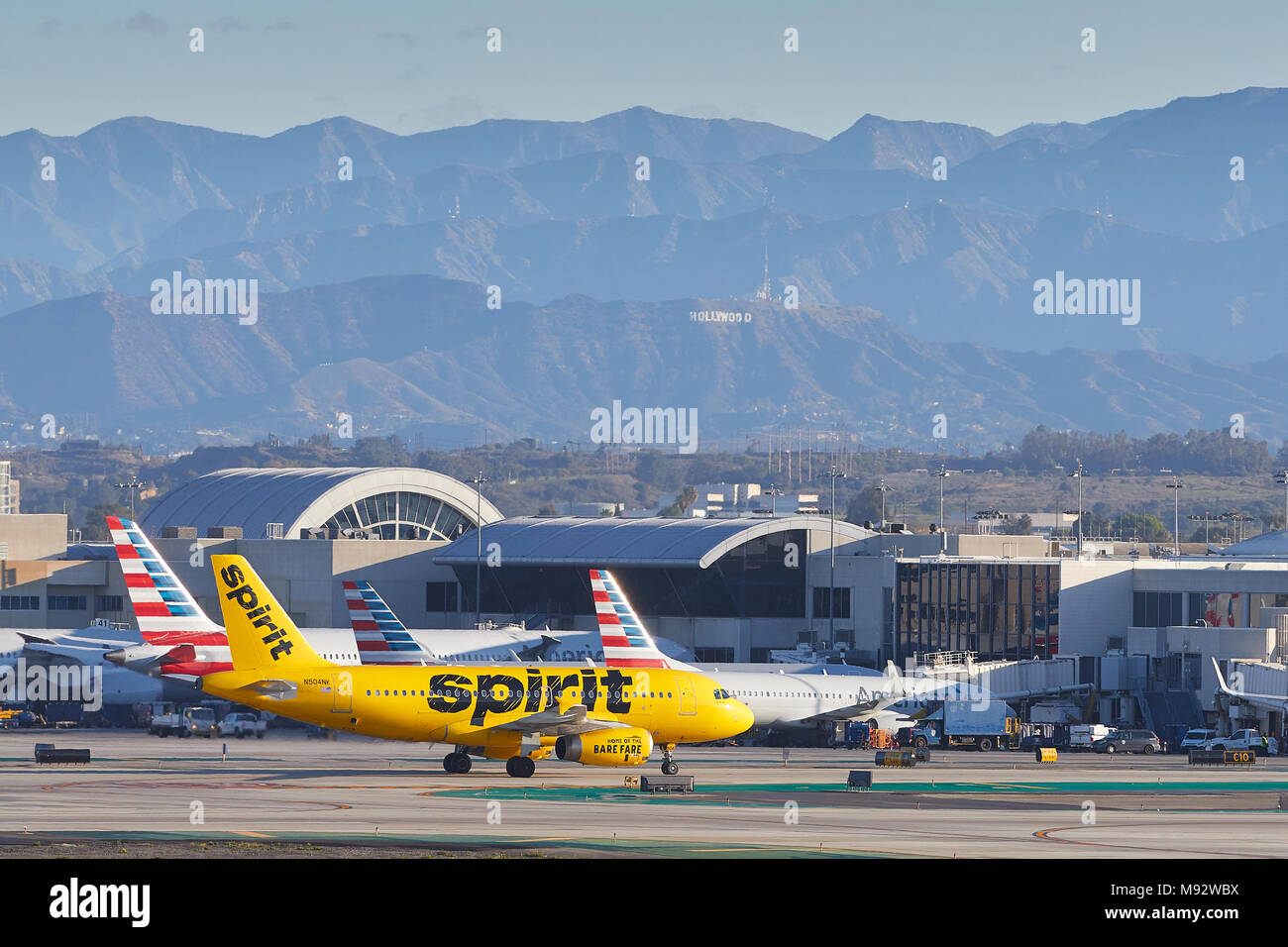Spirito Airlines Airbus A319 di rullaggio verso il terminale dopo l'atterraggio all'Aeroporto Internazionale di Los Angeles LAX. Il segno di Hollywood in background. Foto Stock