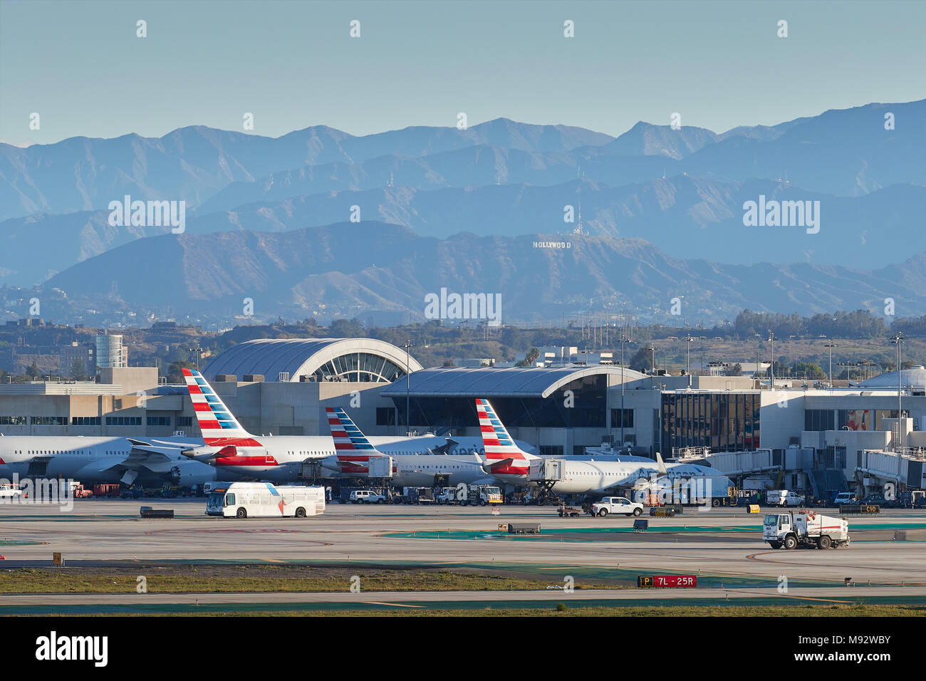 Parcheggiato American Airlines getti di passeggeri nelle prime ore del mattino presso l'Aeroporto Internazionale di Los Angeles LAX. Il segno di Hollywood e le montagne dietro. Foto Stock
