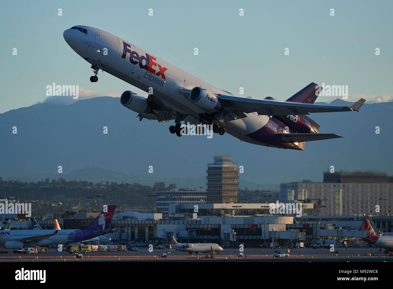 FedEx Express MD11 CARGO Jet decollo dall'Aeroporto Internazionale di Los Angeles LAX, il vecchio il traffico aereo della torre di controllo in background. In California, Stati Uniti d'America. Foto Stock