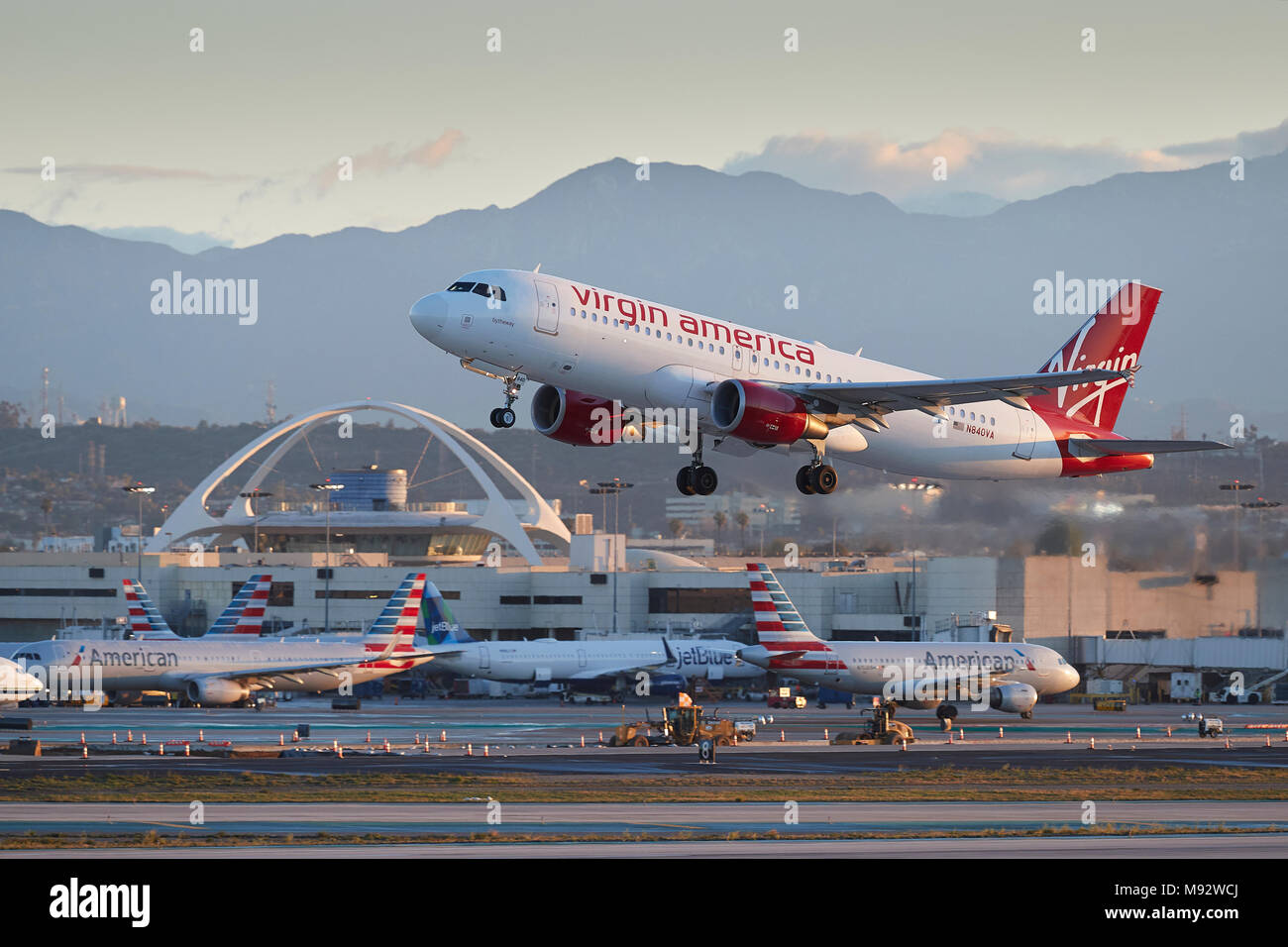 La mattina presto il decollo di un Virgin America Airbus A320 dall'Aeroporto Internazionale di Los Angeles LAX, il tema edificio in background. Foto Stock