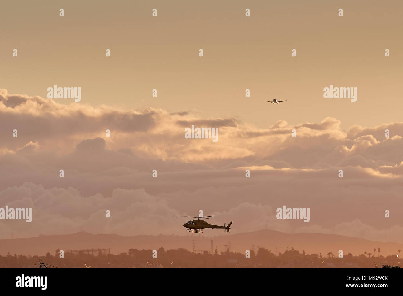 Elicottero passando a sud dell'Aeroporto Internazionale di Los Angeles LAX, a Sunrise. Un aereo Jet su pista approccio a 25 lasciato al di sopra della copertura nuvolosa. Foto Stock