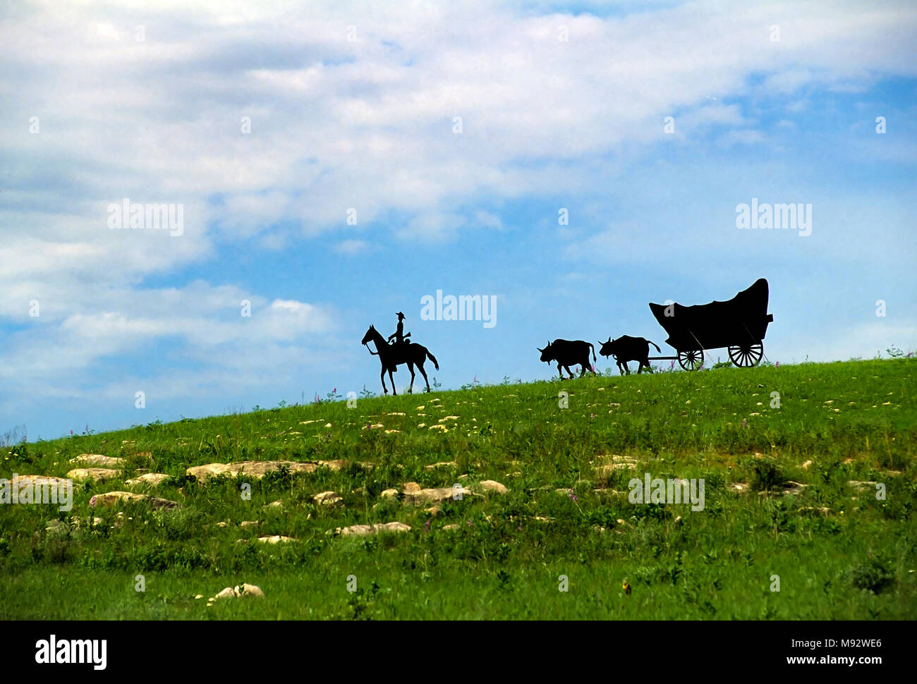 Una scultura di metallo di un cowboy in sella al suo cavallo che conduce un carro conestoga intitolate "Westward Ho', sorge nella pietrina colline vicino al Consiglio Grove, Kansas. Foto Stock