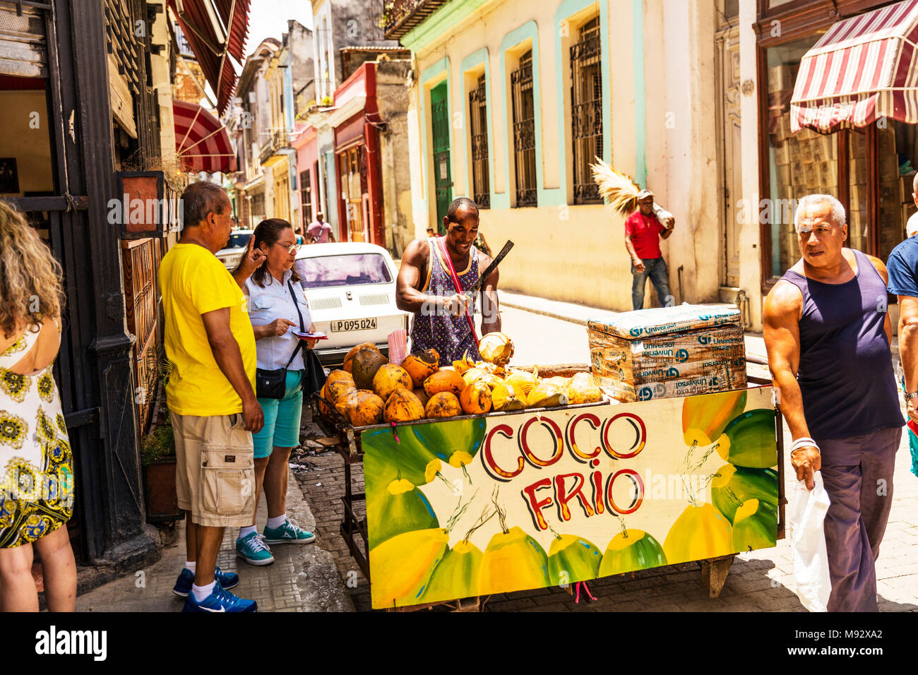 Uomo di cocco vendita bere direttamente dalla noce di cocco, uomo cubano con noci di cocco in stallo, cubana street venditore, Havana street venditore, drink cubano Coco Frio noce di cocco Foto Stock