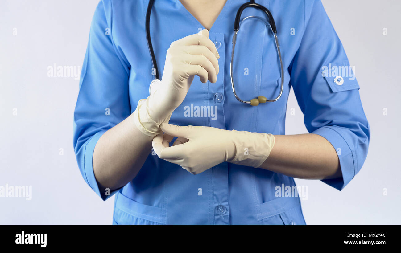 Medico donna mettere dei guanti di gomma, protettivo uniforme, LAVORATORE DI LABORATORIO Foto Stock