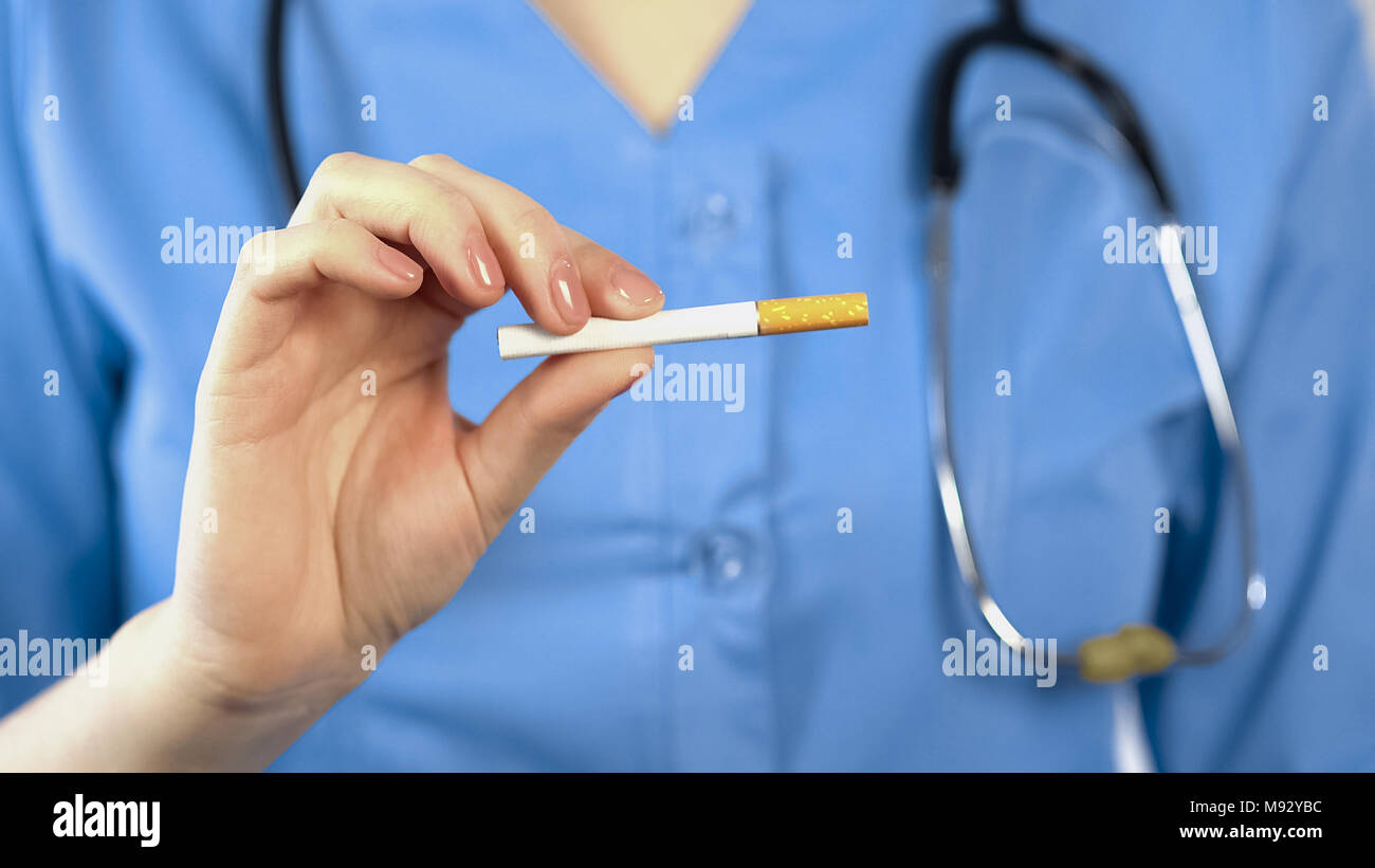 Terapista del sesso femminile che mostra sigaretta, avvertimento circa i rischi per la salute del fumo Foto Stock