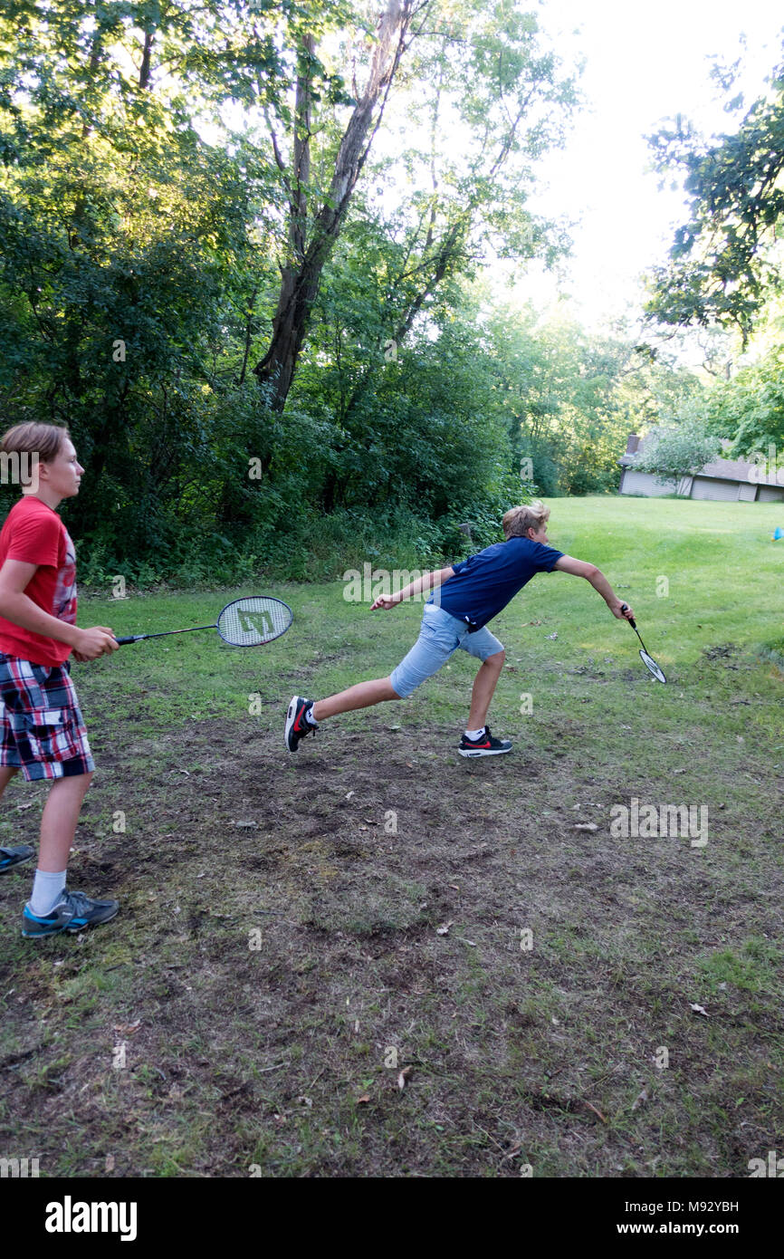 Ragazzo adolescente si allunga per tornare volano in un gioco di erba badminton. Clitherall Minnesota MN USA Foto Stock