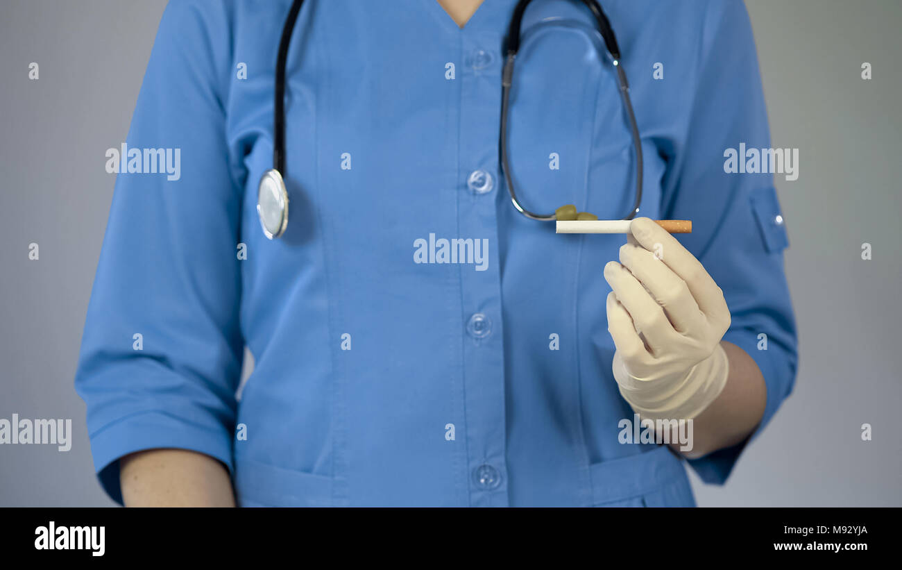 Medico donna azienda sigaretta in mano, avviso di cancro, cattiva abitudine delle tossicodipendenze Foto Stock