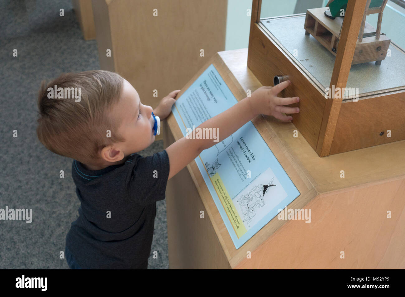 Il Toddler spingendo il pulsante per il controllo della macchina a moto presso il Museo della Scienza del Minnesota. St Paul Minnesota MN USA Foto Stock