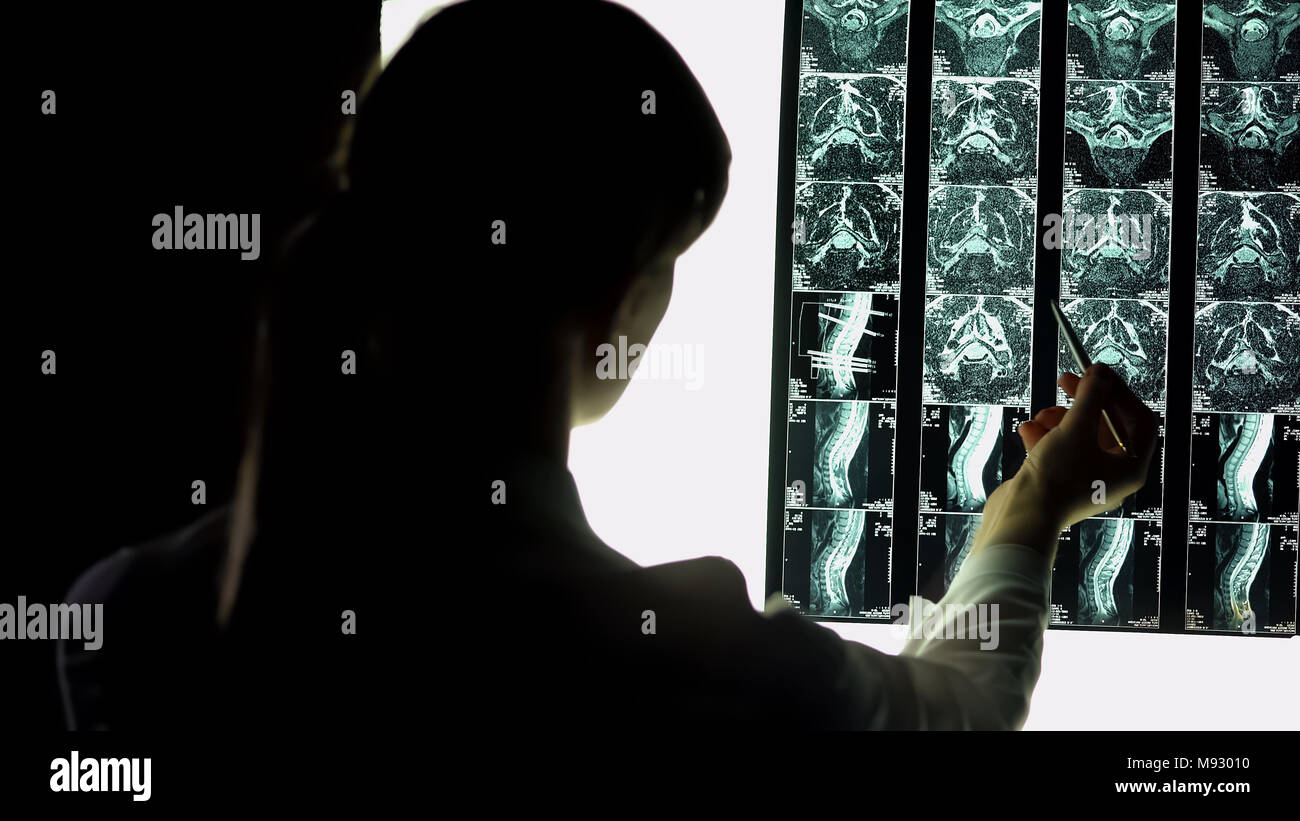Femmina medico ospedaliero attentamente il paziente di controllo a raggi x e di esame del pregiudizio Foto Stock
