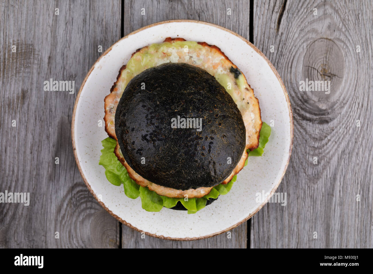 Cucinata fresca hamburger con rotolo di colore nero, verdure e salmone cotoletta. Sandwich fatti in casa, vista dall'alto Foto Stock