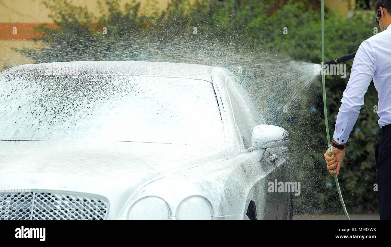 Chauffeur il lavaggio di automobile di lusso con schiuma, lavoro responsabile, business Foto Stock