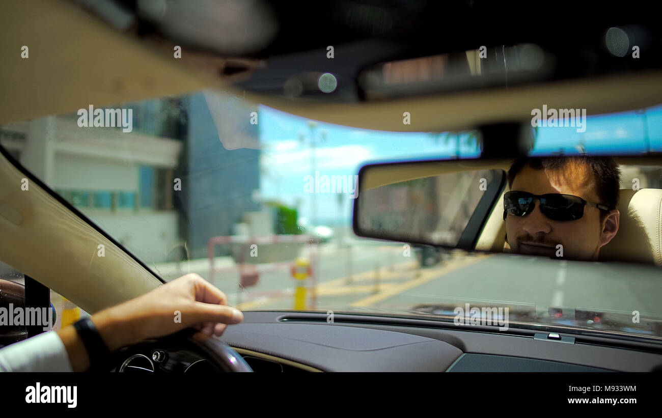 Lieto uomo in occhiali da sole auto pilotaggio, riflessione a specchio  retrovisore, vacanze Foto stock - Alamy