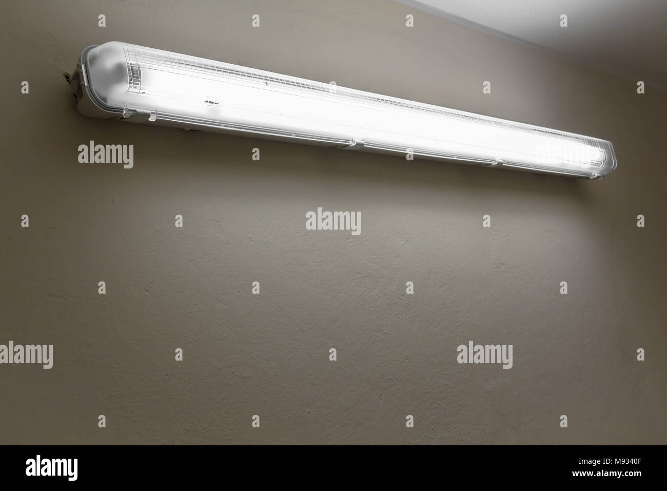 Una vecchia lampada al neon si illumina con luce debole, un bianco muro di cemento. Spazio per il testo. Foto Stock