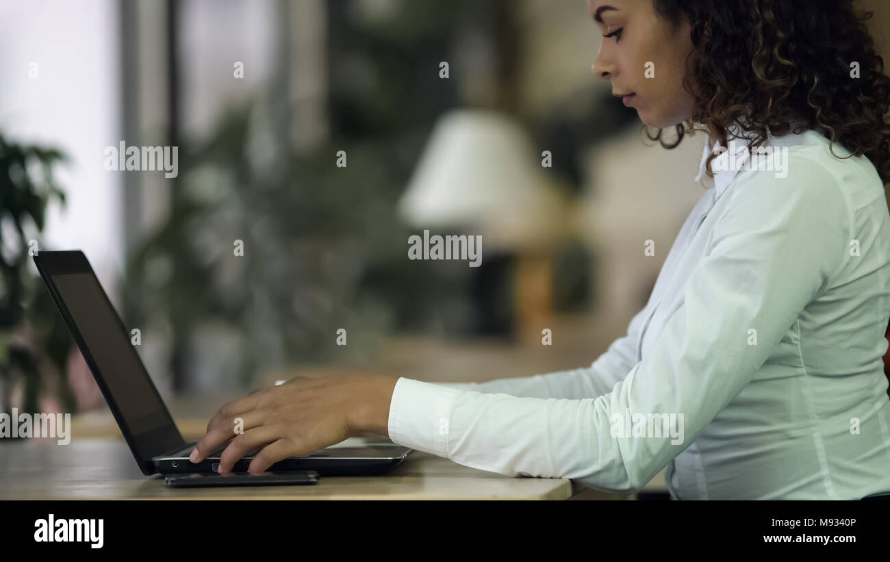 Donna al lavoro su laptop, telefono e carte sulla scrivania, atmosfera all ufficio della società Foto Stock