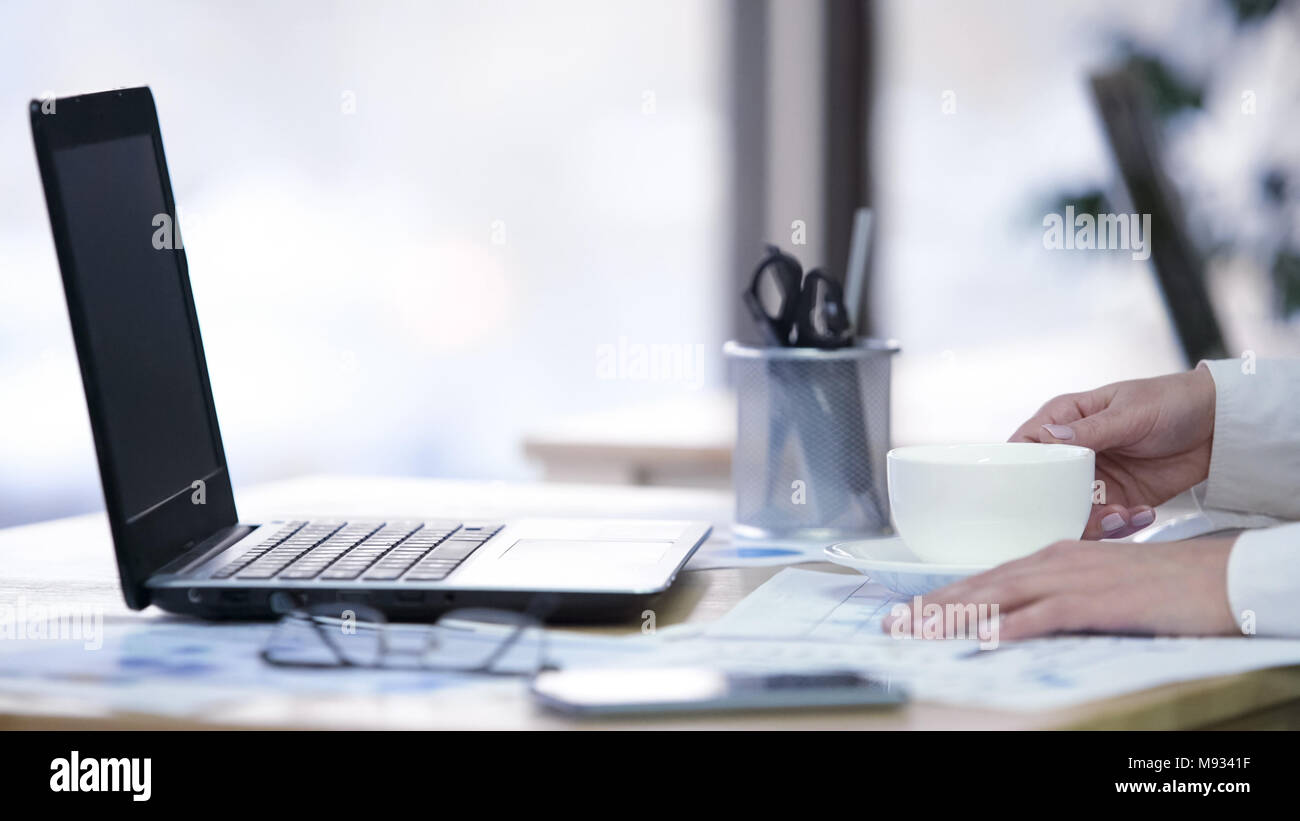 Mani femminili holding tazza di caffè, segretario avente break al posto di lavoro, primo piano Foto Stock