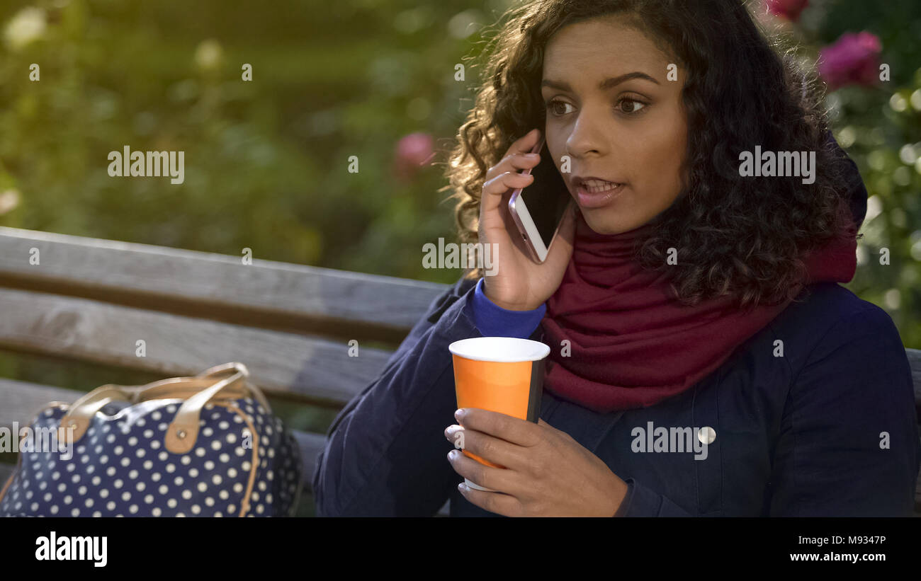 Attraente razza mista Donna che parla al telefono e di bere il caffè all'aperto Foto Stock