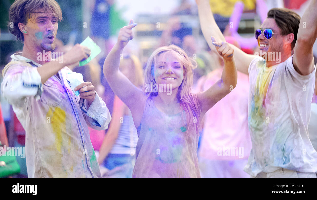 I giovani allegri gettare polvere colorata in aria, ballare al festival Foto Stock