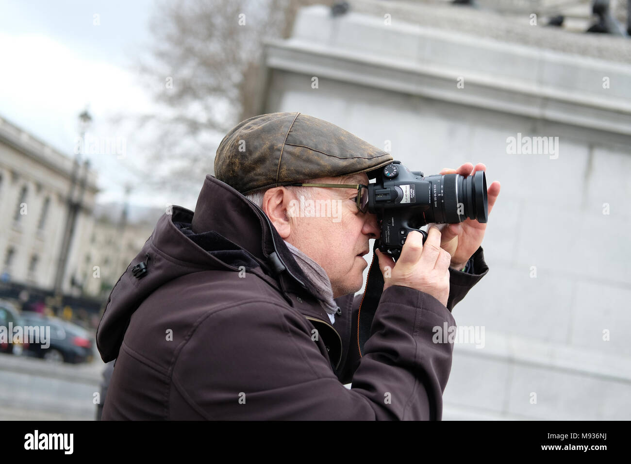 Un turista scattano fotografie in Trafalgar Square a Londra. Foto Stock