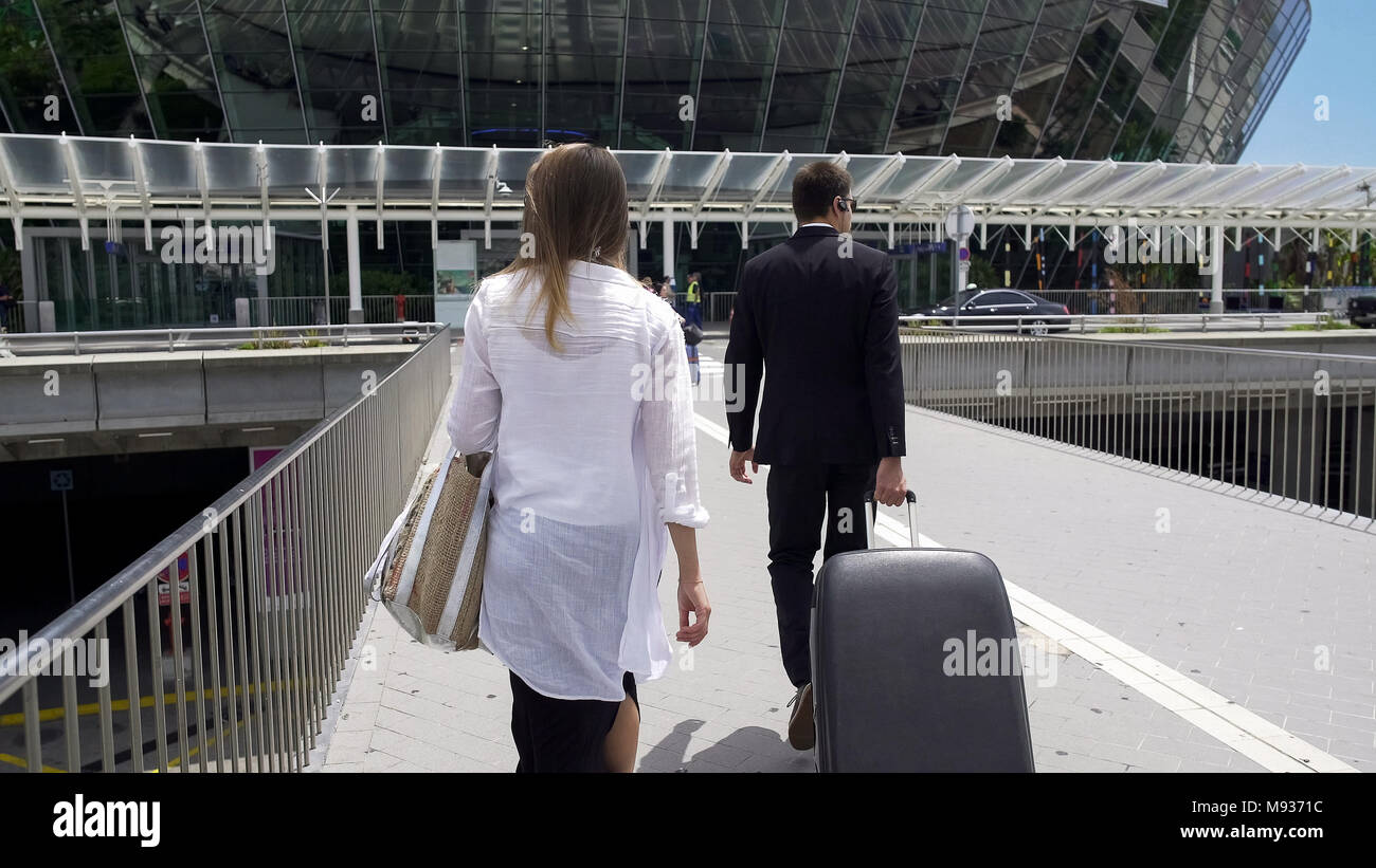 Femmina glamour e la guardia del corpo con i suoi bagagli a piedi aeroporto, turismo Foto Stock