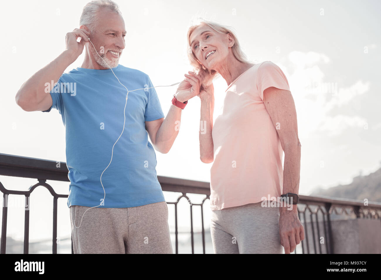 Piacevole coppia senior in piedi e ascolto di musica. Foto Stock