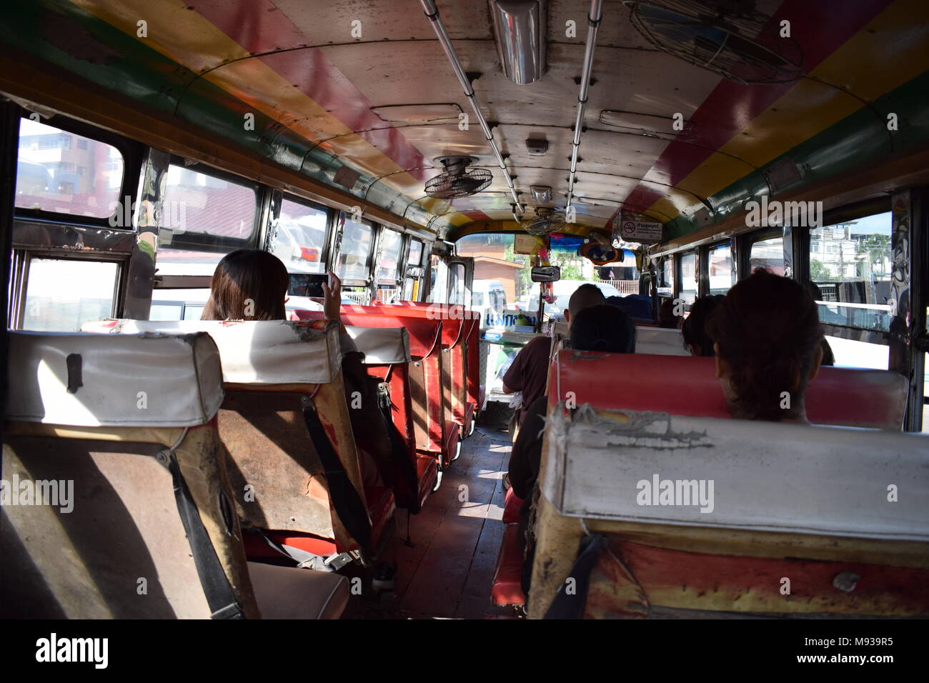 Girato dal retro di un vecchio arrugginito e strappato thailandese bus dall' ultimo sedi in Amphawa, Thailandia con ventole DIY sul tetto per AC. Foto Stock