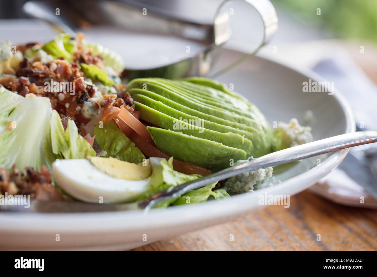 La cena insalata Cobb fatta con lattuga romana, pomodori, uova, avocado e pancetta con ranch dressing sul lato Foto Stock