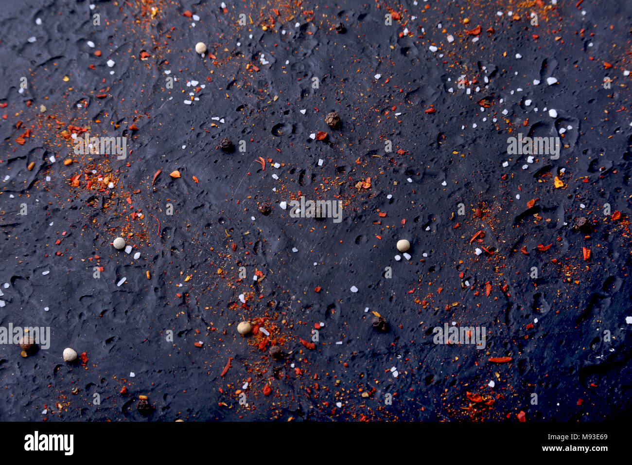 Red spezie, sale e pepe in marmo nero. Abstract di nero lo sfondo. Vista dall'alto. Foto Stock