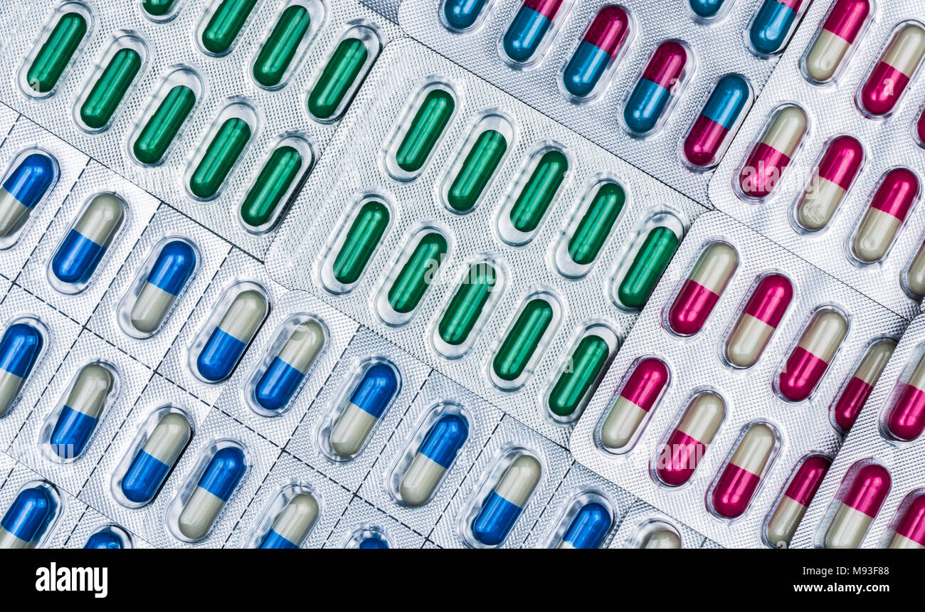 Telaio piena di colorati pillole di capsule in blister disposti con belle pattern. Gli imballaggi di prodotti farmaceutici. Medicina per le infezioni malattia. Foto Stock